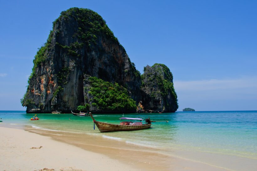 A boat sits at anchor in front of one of the famous karsts (rock formations) near Phra Nang Beach in Krabi, Thailand.